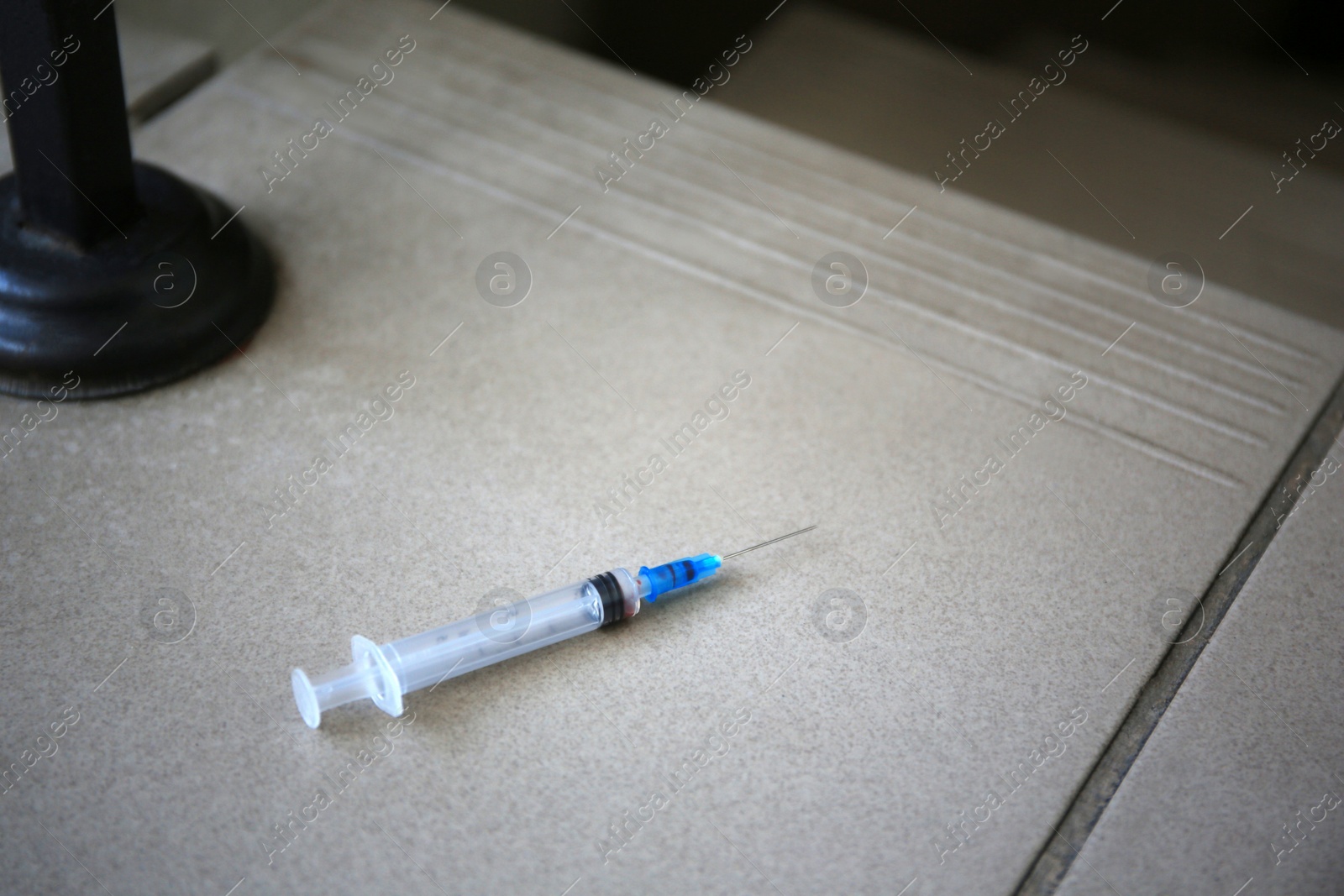 Photo of Disposable syringe with needle on tiled stairs indoors. Space for text