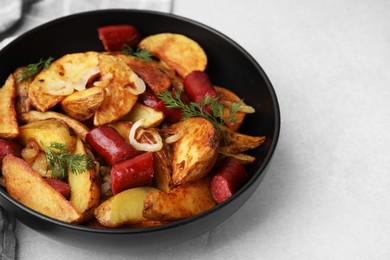 Photo of Delicious baked potato with thin dry smoked sausages, onion and dill in bowl on gray table, closeup