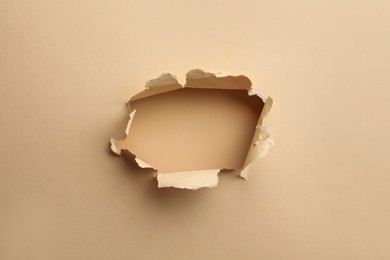 Hole in light beige paper on color background
