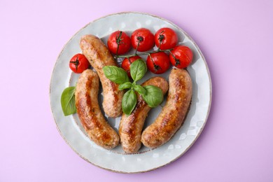 Plate with tasty homemade sausages, basil leaves and tomatoes on violet table, top view