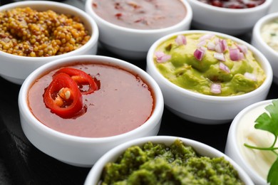 Photo of Different tasty sauces in bowls on board, closeup