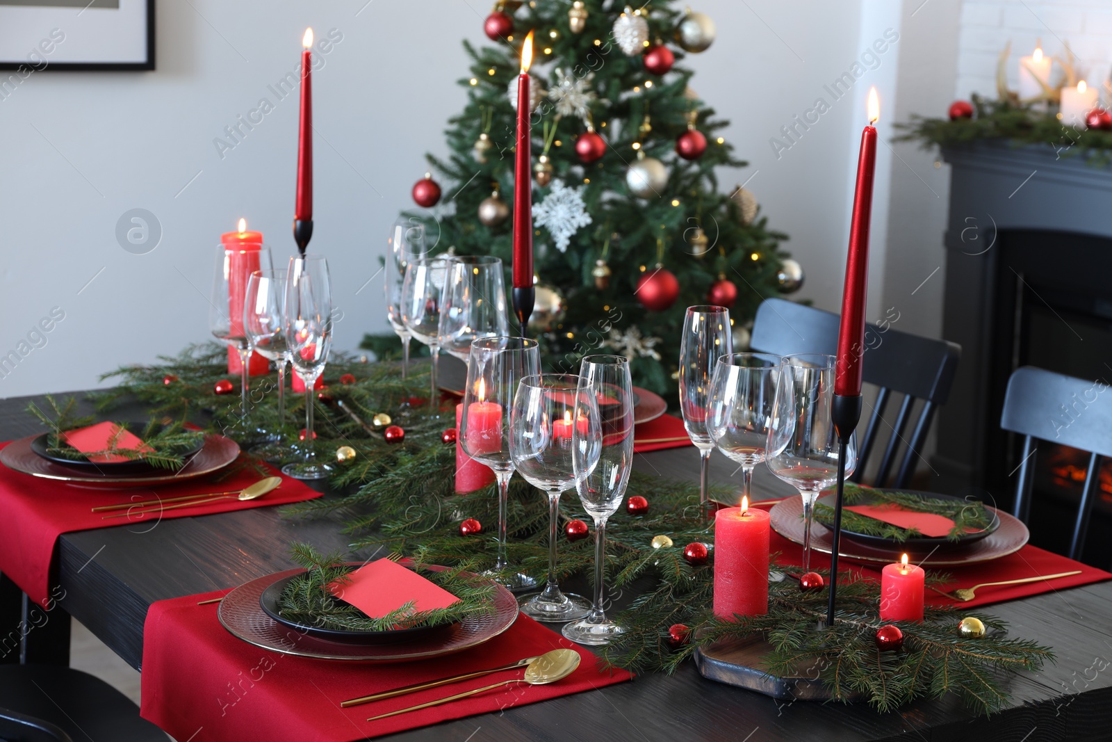 Photo of Elegant Christmas table setting with dishware and burning candles in festively decorated room