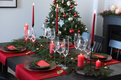 Elegant Christmas table setting with dishware and burning candles in festively decorated room