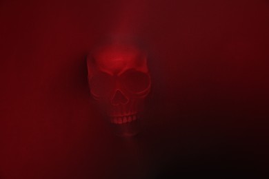 Silhouette of creepy ghost with skull behind red cloth