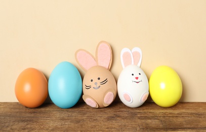 Photo of Two eggs as bunnies among others on wooden table against beige background. Easter celebration