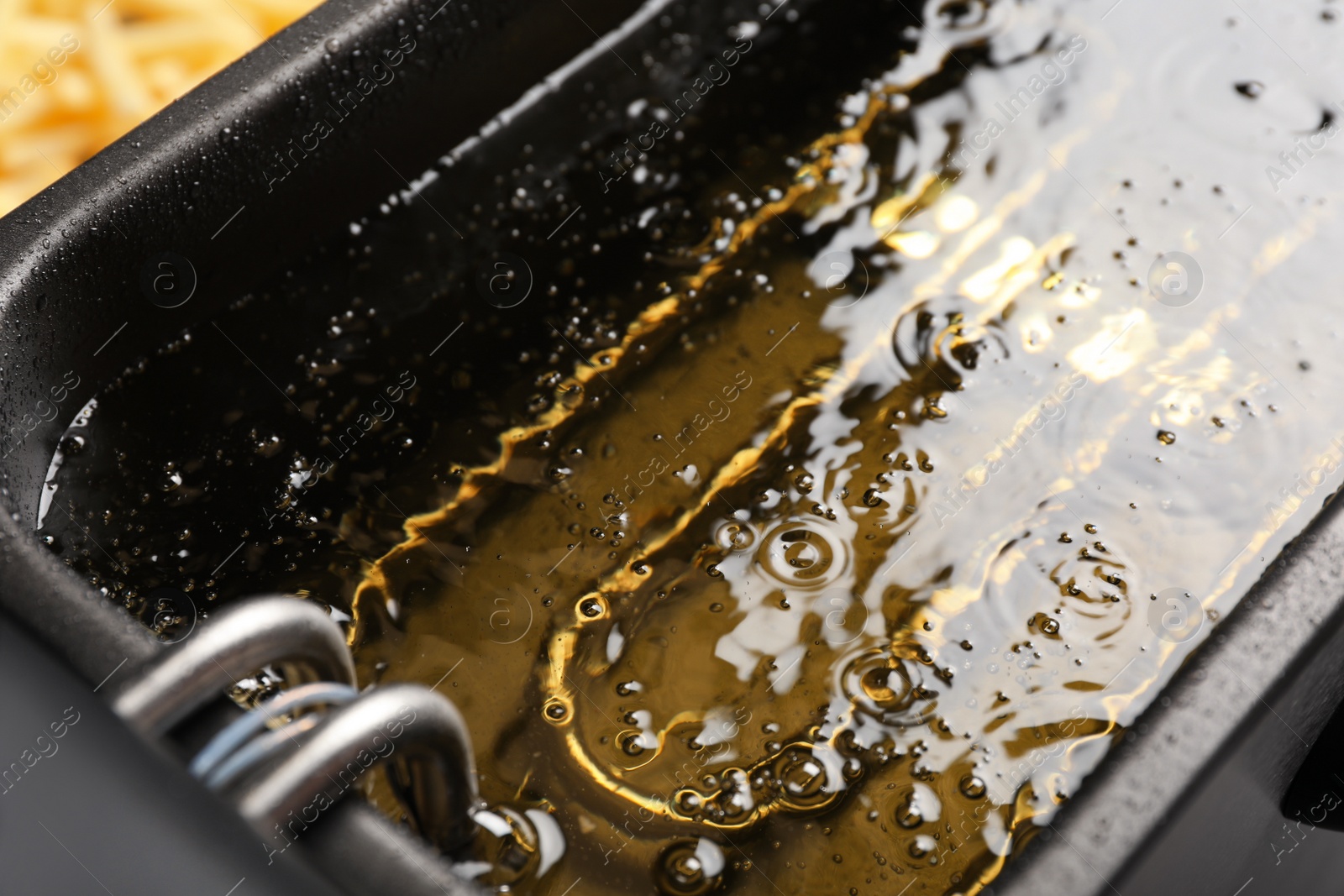 Photo of Hot cooking oil in deep fryer, closeup