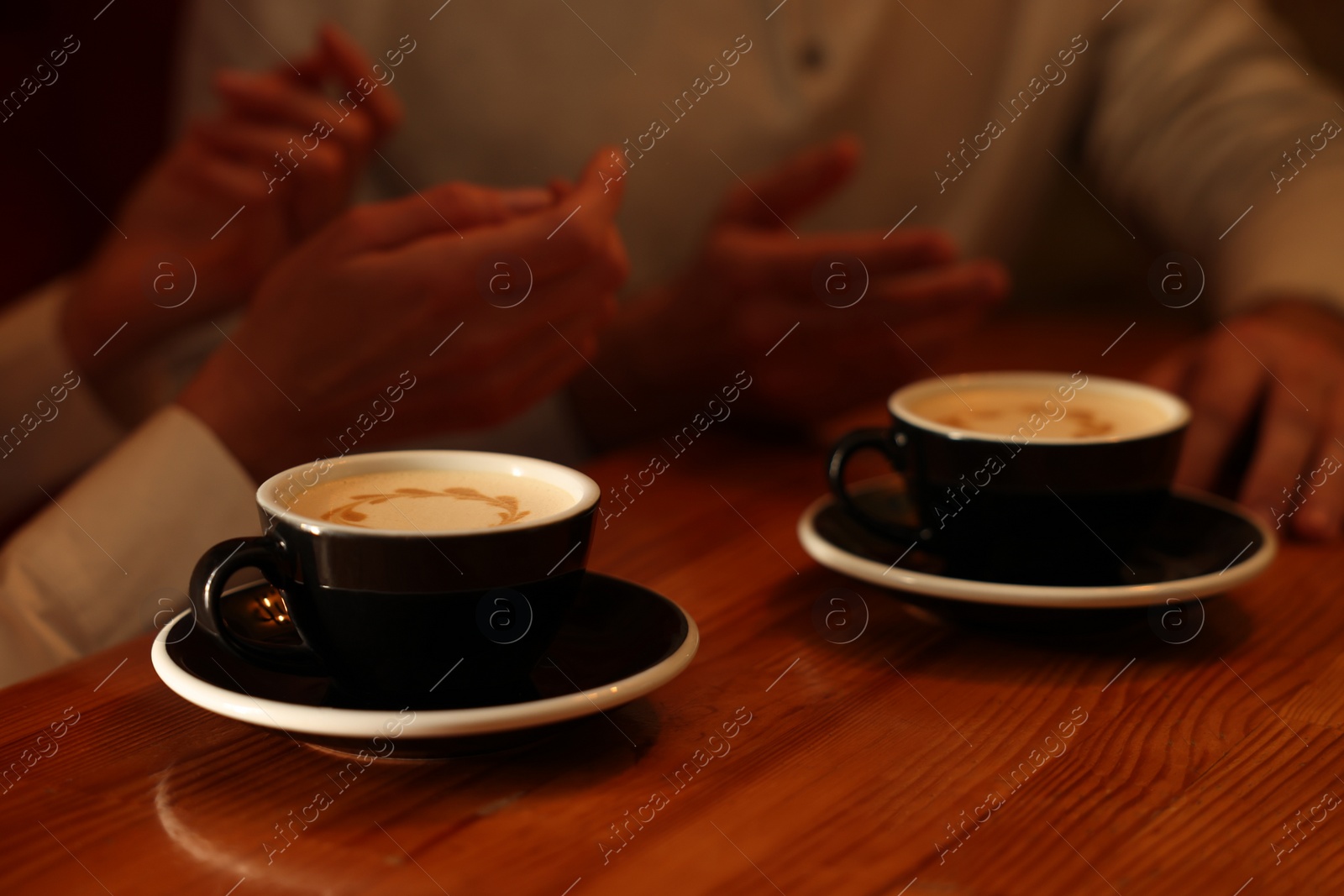 Photo of Couple with cups of aromatic coffee at wooden table, closeup