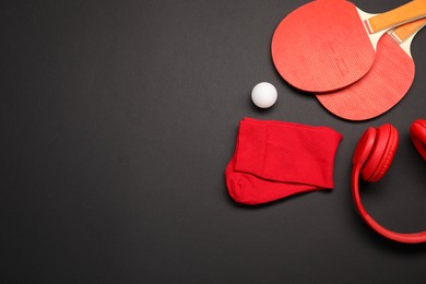 Sports equipment. Ping pong rackets, ball, headphones and socks on black background, flat lay. Space for text