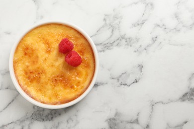 Photo of Delicious creme brulee with raspberries on white marble table, top view. Space for text