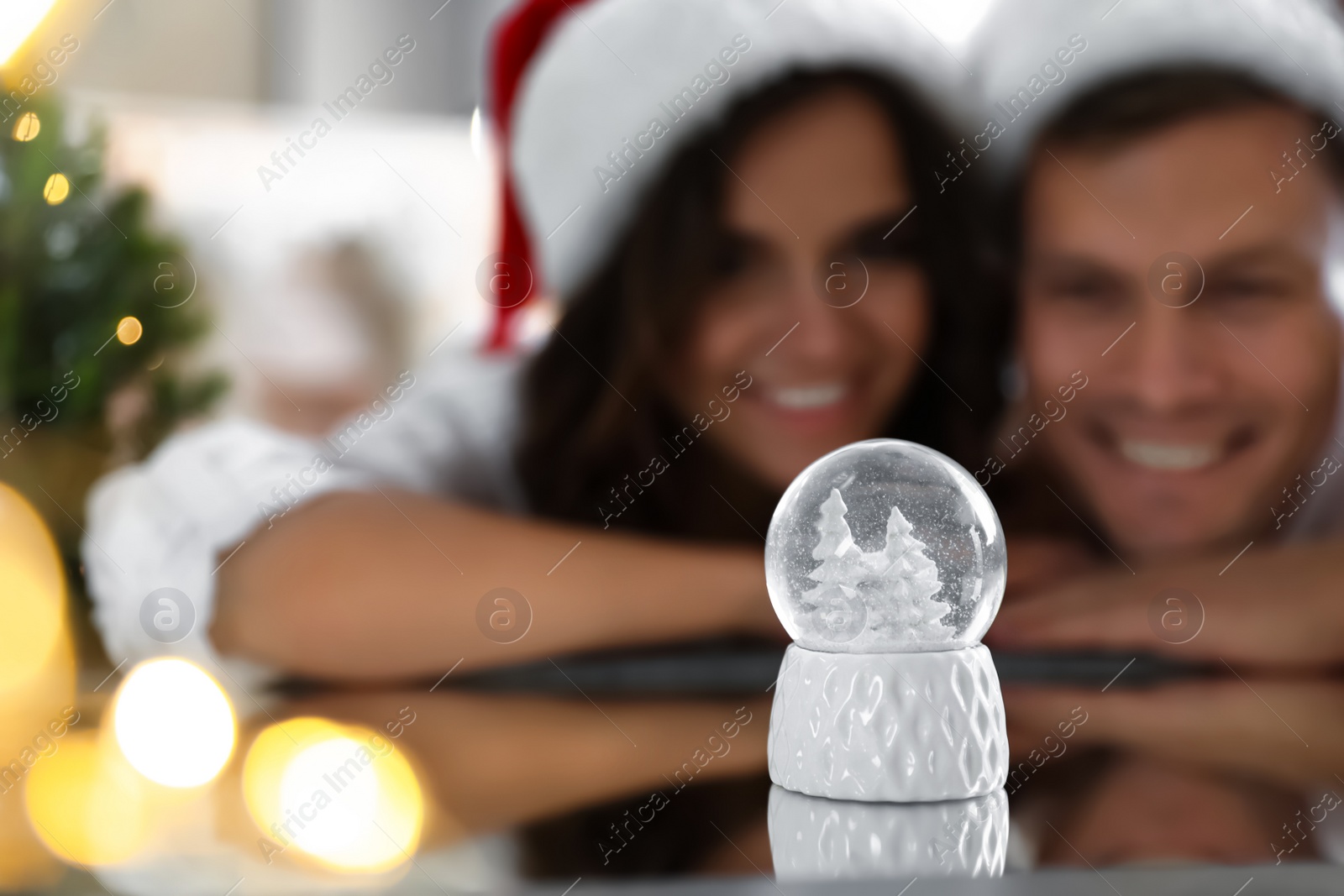 Photo of Snow globe on mirror surface. Happy couple celebrating Christmas