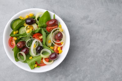 Photo of Bowl of tasty salad with leek and olives on grey table, top view. Space for text