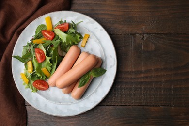 Delicious boiled sausages with salad on wooden table, top view. Space for text