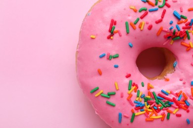 Photo of Tasty glazed donut decorated with sprinkles on pink background, closeup. Space for text