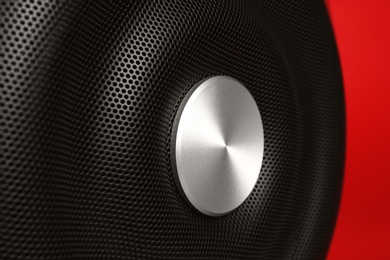 Photo of Modern subwoofer on red background, closeup. Powerful audio speaker