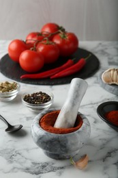 Photo of Mortar with red curry paste and ingredients on white marble table