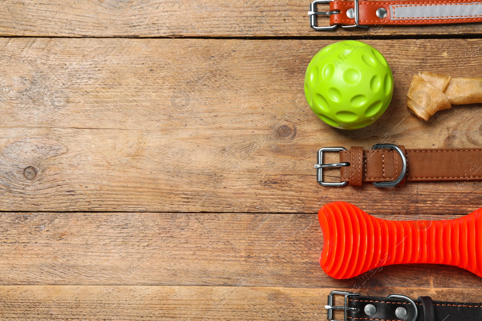 Photo of Flat lay composition with dog collars and toys on wooden table. Space for text