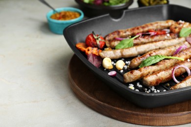 Photo of Grill pan with tasty sausages and vegetables on light table, closeup. Space for text