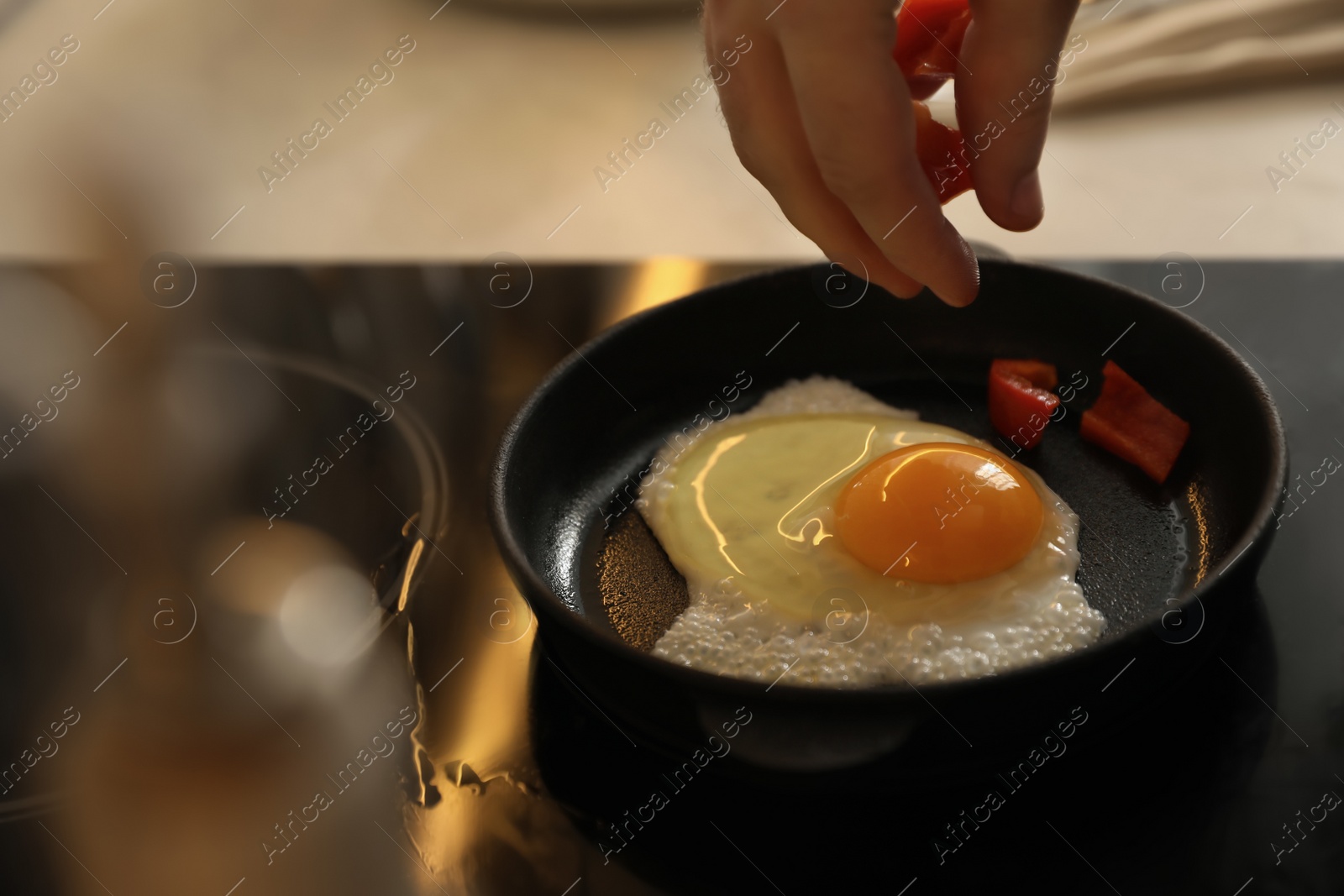Photo of Man cooking egg in small frying pan, closeup