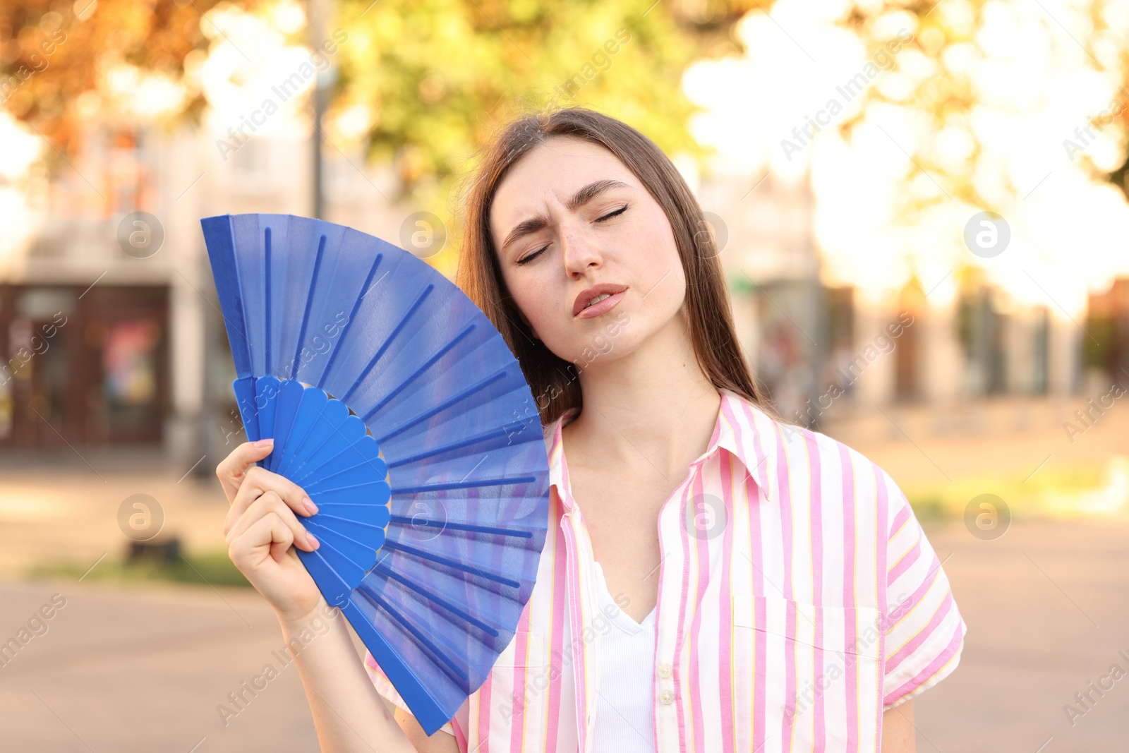 Photo of Woman with hand fan suffering from heat outdoors