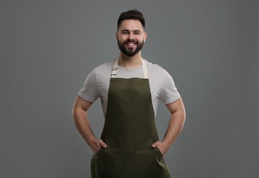 Smiling man in kitchen apron on grey background. Mockup for design