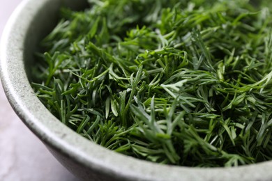 Photo of Fresh cut dill in bowl on table, closeup