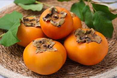 Delicious ripe juicy persimmons on wicker mat, closeup