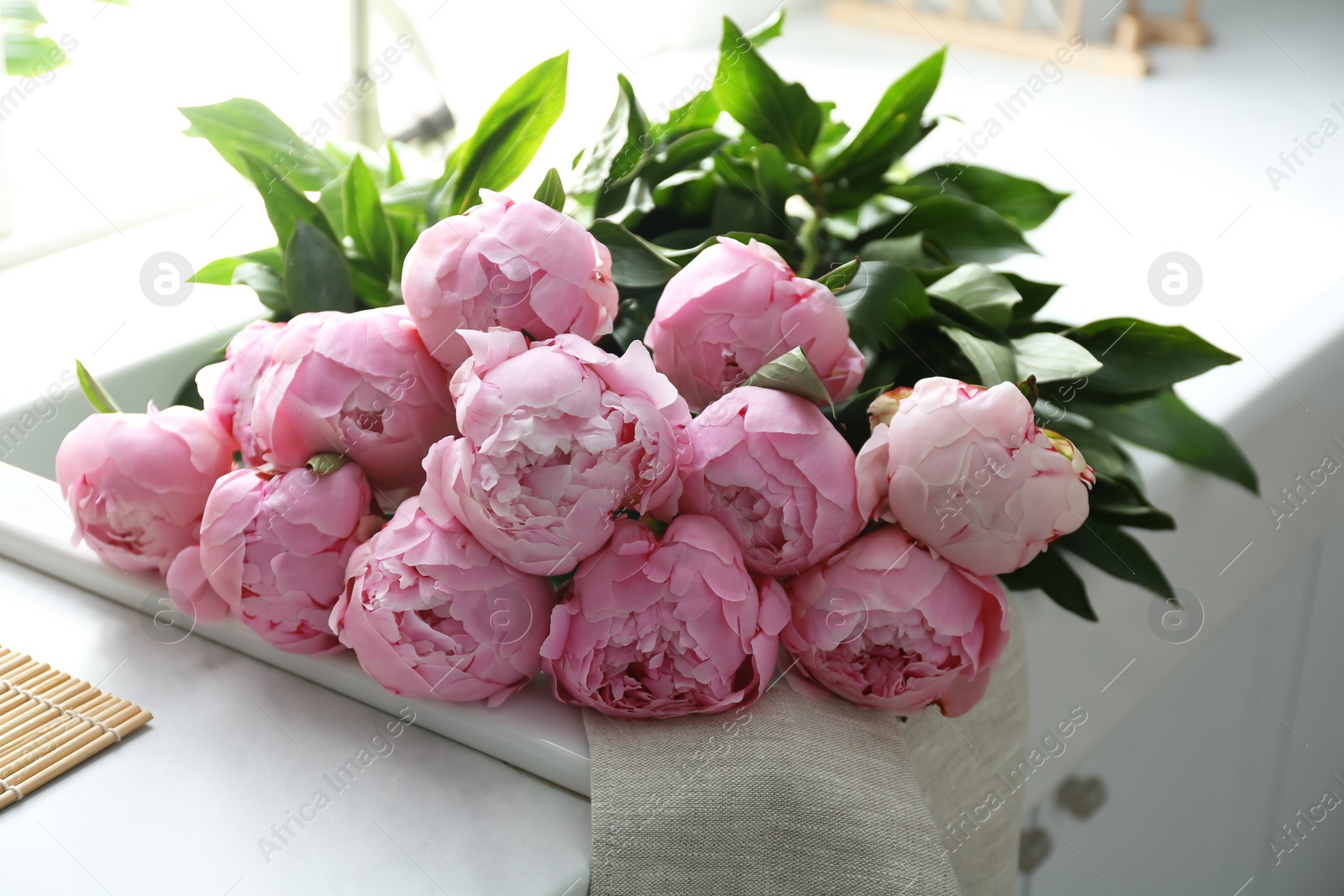 Photo of Bouquet of beautiful pink peonies on counter in kitchen