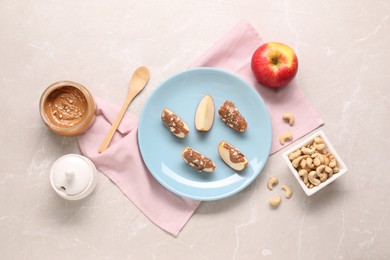 Photo of Slices of fresh apple with nut butter and cashews on light marble table, flat lay