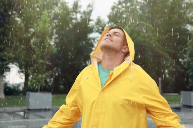 Photo of Man with raincoat walking under rain in park