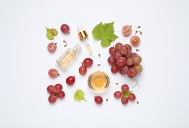 Photo of Organic red grapes, seeds and natural essential oil on white background, top view