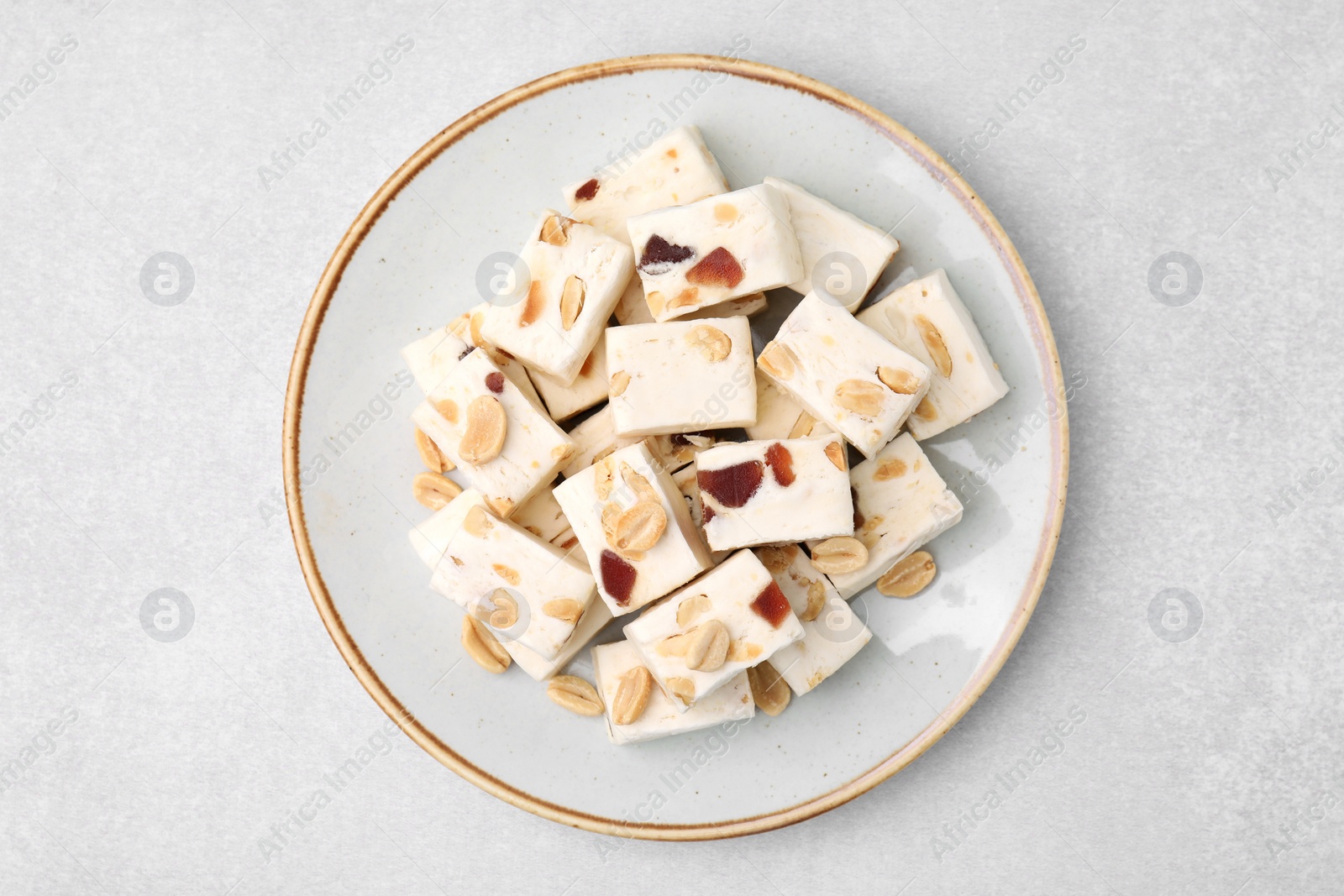 Photo of Pieces of delicious nutty nougat on light gray table, top view