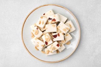 Photo of Pieces of delicious nutty nougat on light gray table, top view