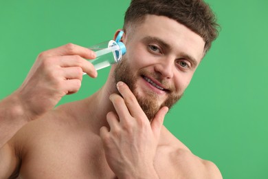Photo of Handsome man applying lotion onto his face on green background