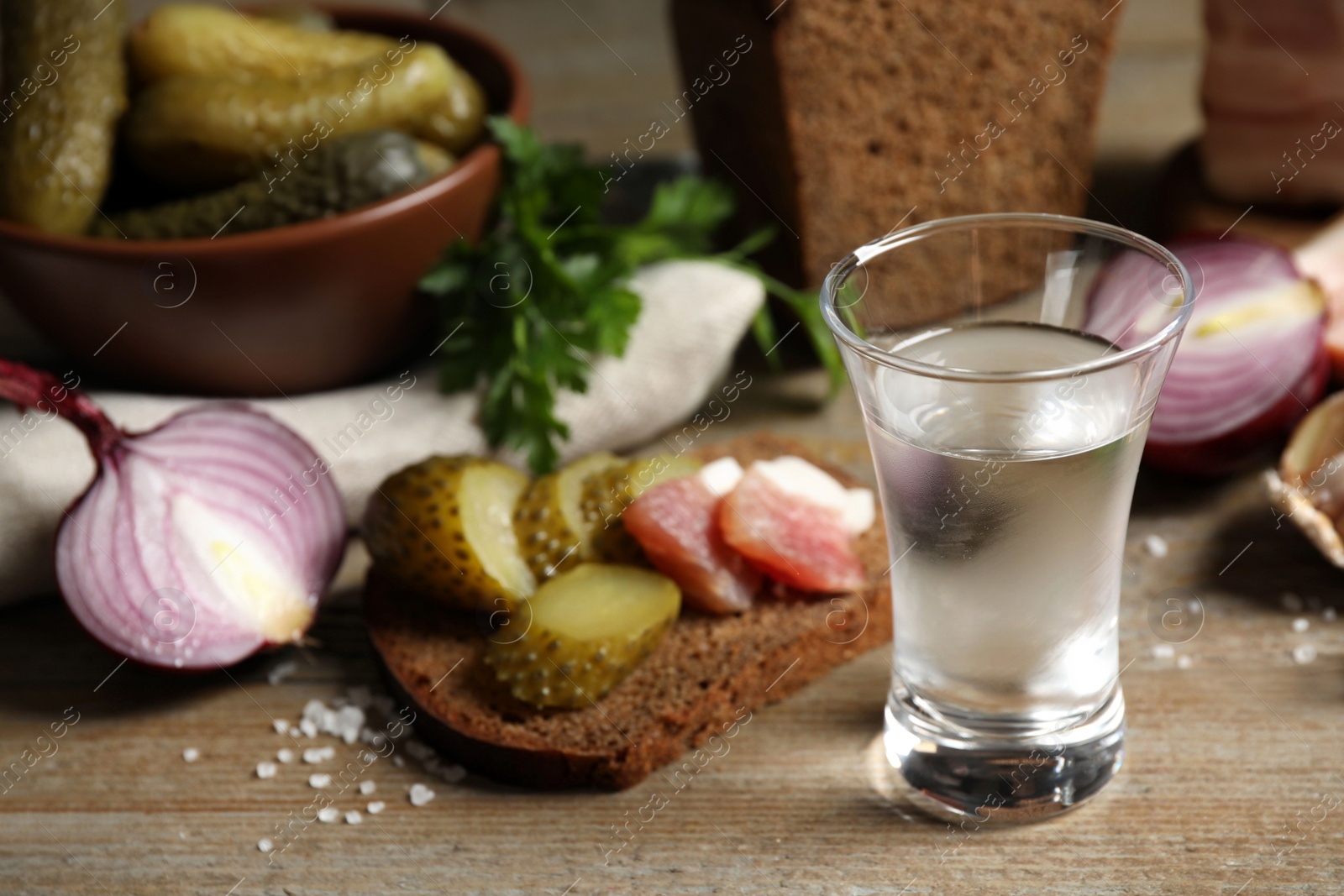 Photo of Cold Russian vodka with snacks on wooden table, closeup