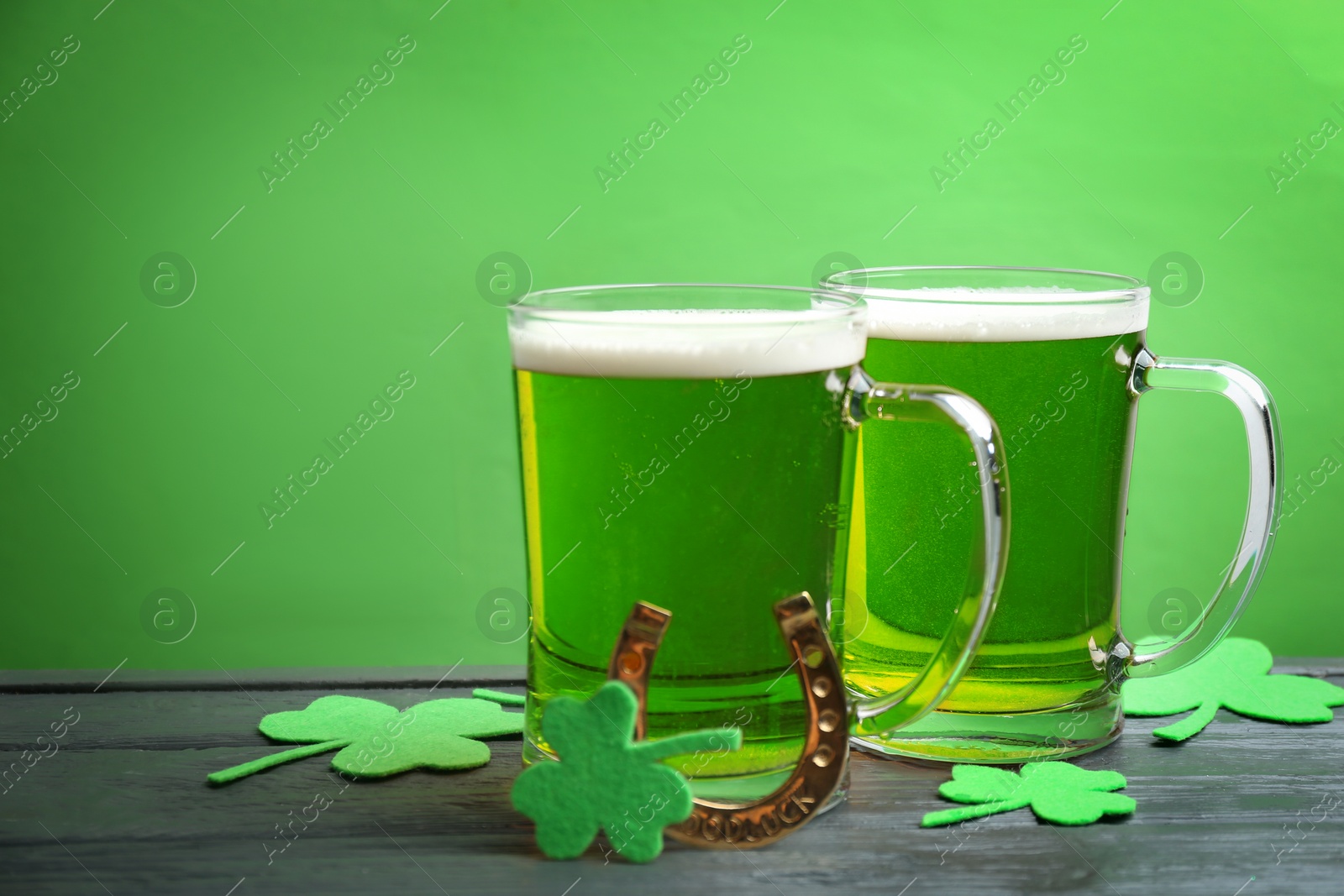 Photo of Green beer, horseshoe and clover leaves on wooden table. St. Patrick's Day celebration