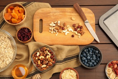 Photo of Making granola. Nuts, blueberries and other ingredients on wooden table, flat lay