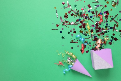 Photo of Flat lay composition of colorful confetti, party cracker and box on green background. Space for text
