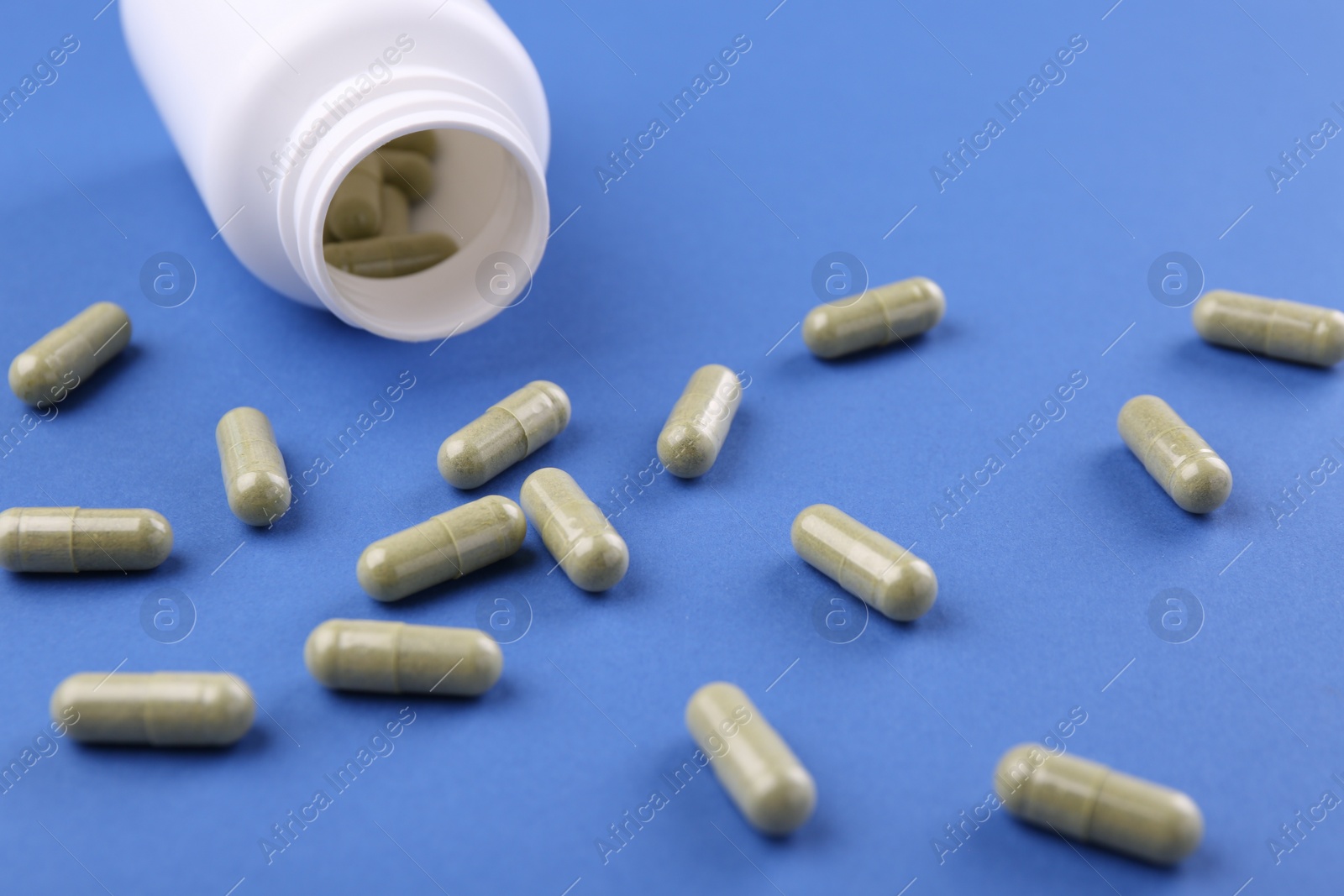 Photo of Bottle and vitamin capsules on blue background, closeup