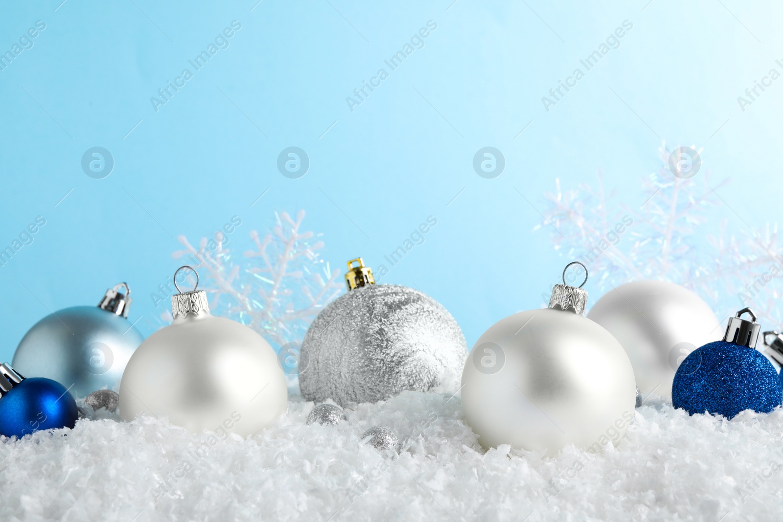 Photo of Christmas tree decoration on artificial snow against light blue background