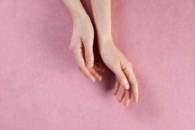 Photo of Woman with beautiful hands on pink fabric, top view