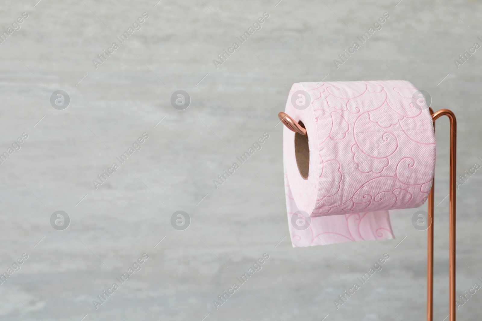 Photo of Holder with toilet paper roll on gray background. Space for text