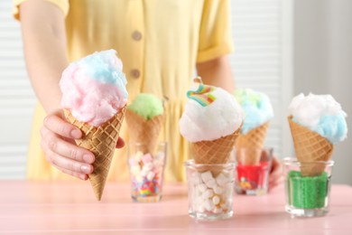 Woman holding waffle cone with cotton candy indoors, closeup