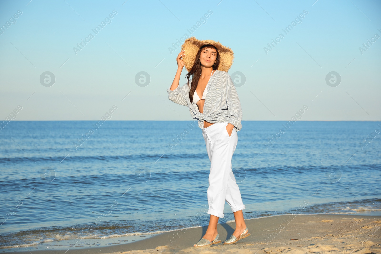 Photo of Beautiful young woman in straw hat on beach