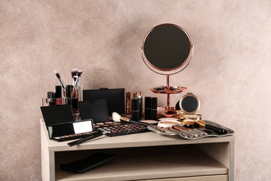 Dressing table with beauty accessories near color wall in room