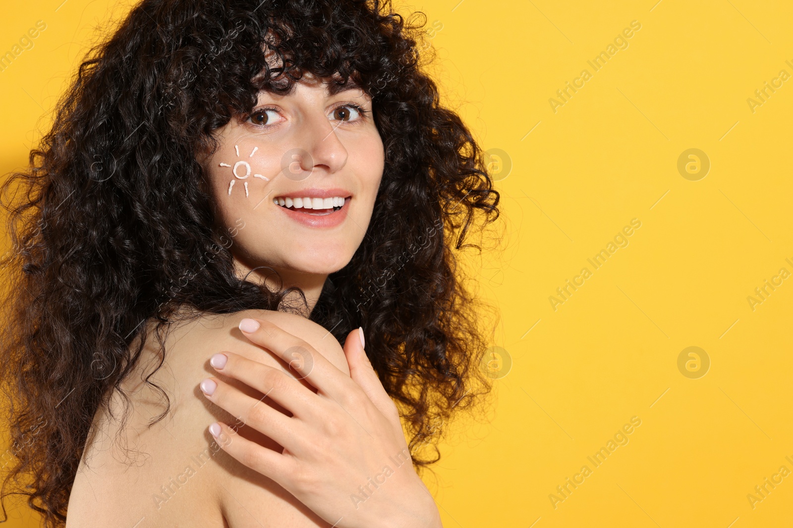 Photo of Beautiful happy woman with sun protection cream on her face against orange background, space for text