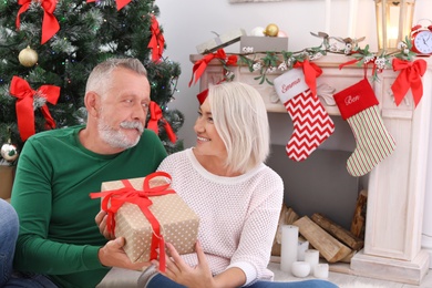 Mature couple with Christmas gift box at home