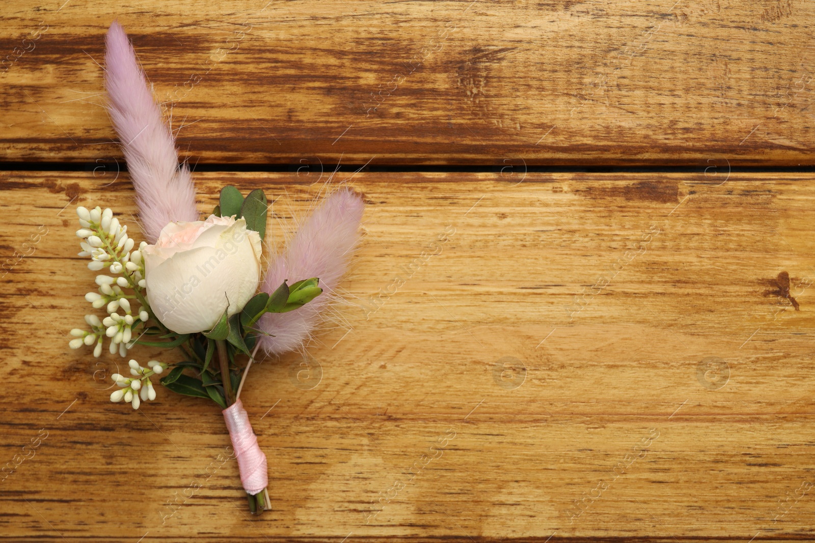 Photo of Small stylish boutonniere on wooden table, top view. Space for text