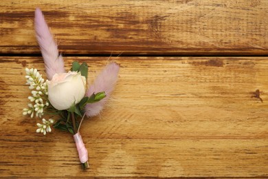 Small stylish boutonniere on wooden table, top view. Space for text