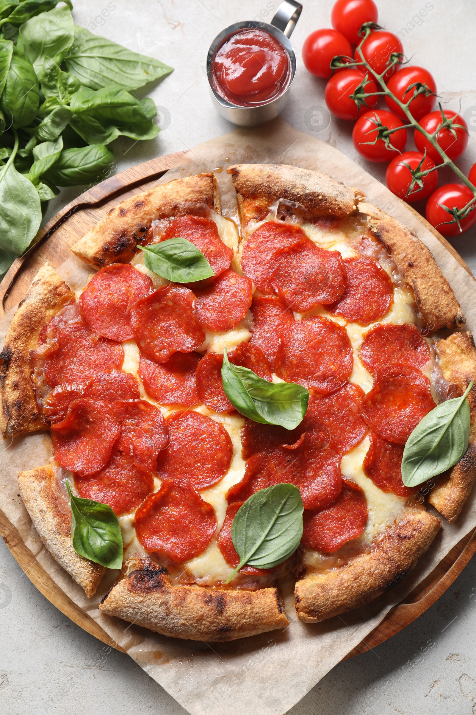 Photo of Tasty pepperoni pizza with basil, sauce and tomatoes on grey table, top view