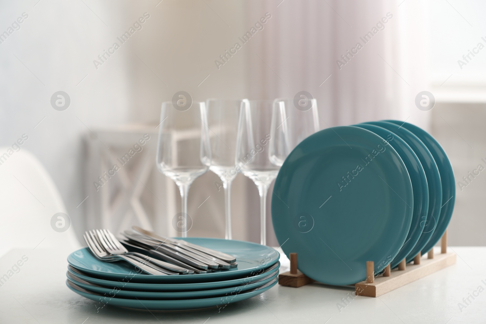 Photo of Set of clean dishes, cutlery and wineglasses on white table indoors